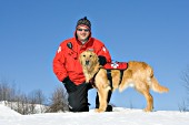 Ski patroller with golden retriever rescue dog